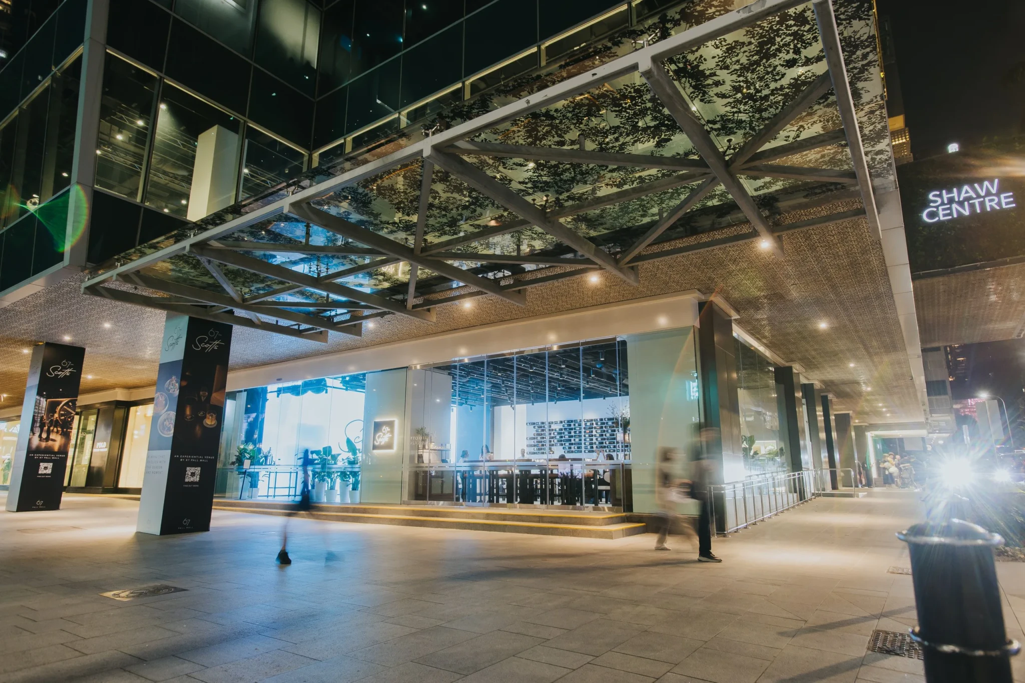 The glass facade of 67 on Scotts at Shaw Centre, lit up at night
