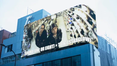 A curved LED billboard showing SOUMA and TAIKI promoting ONE WHO GLOWS
