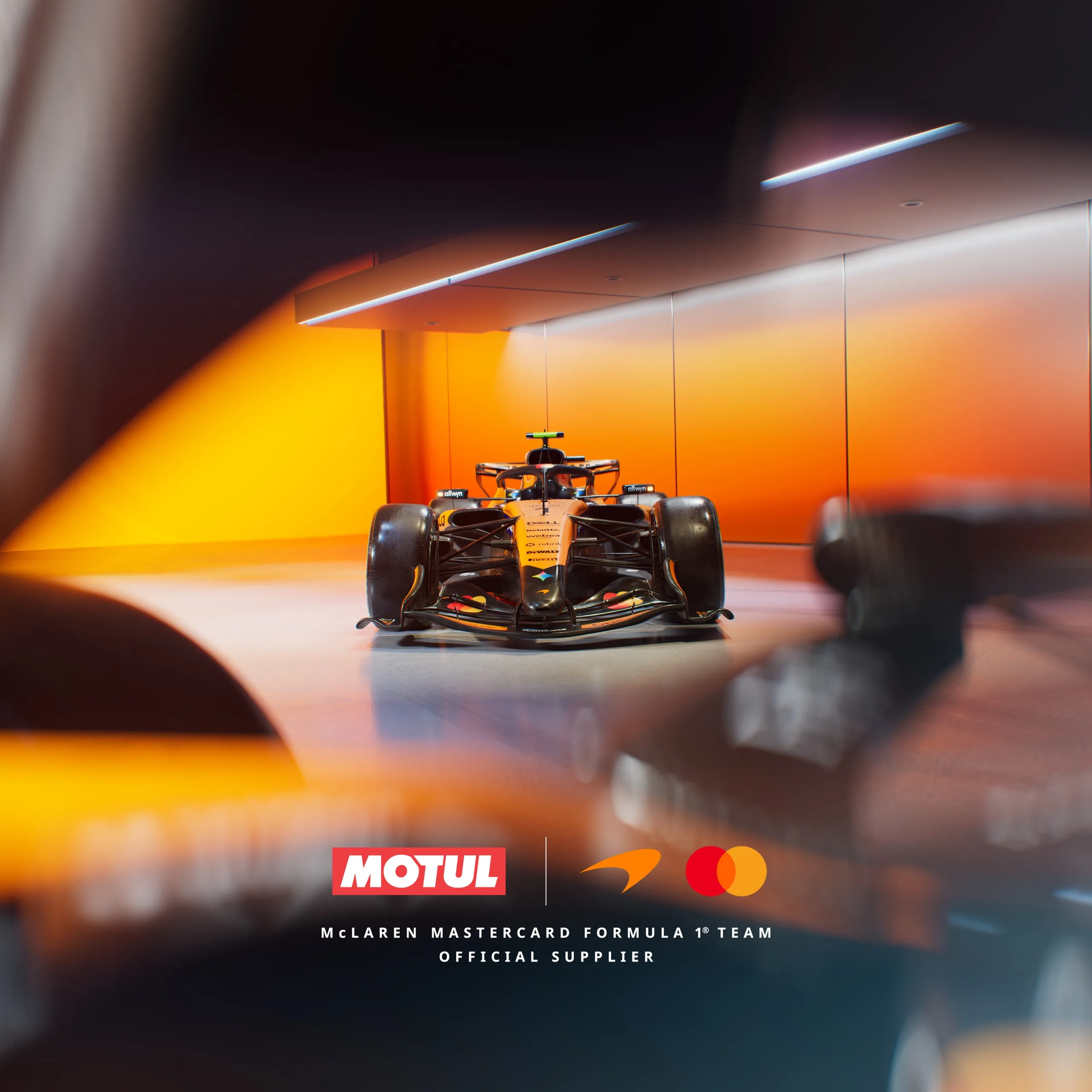 McLaren Formula 1 car in orange-lit facility with Motul partnership branding