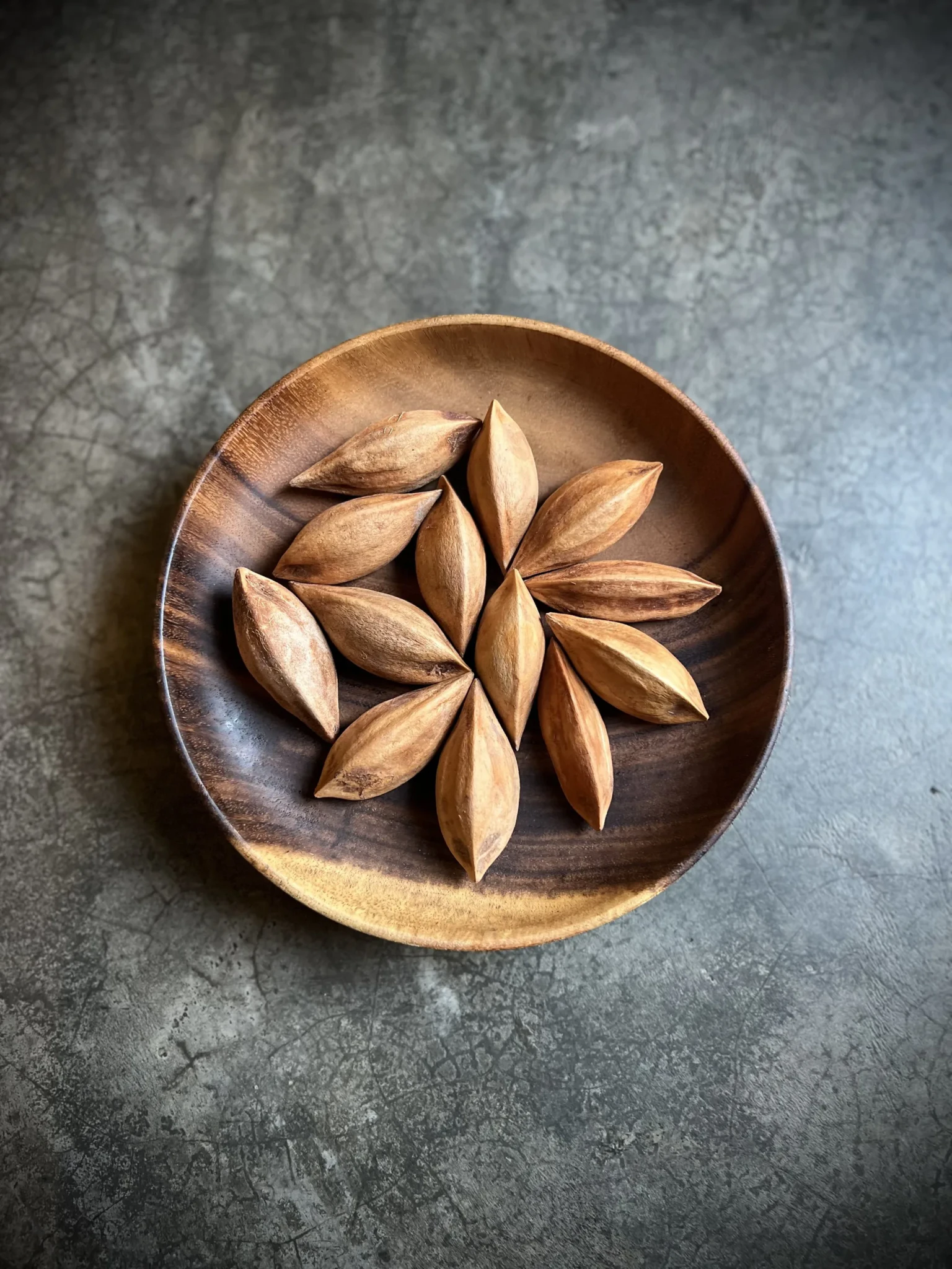 Pili nuts in a wooden bowl on a concrete surface