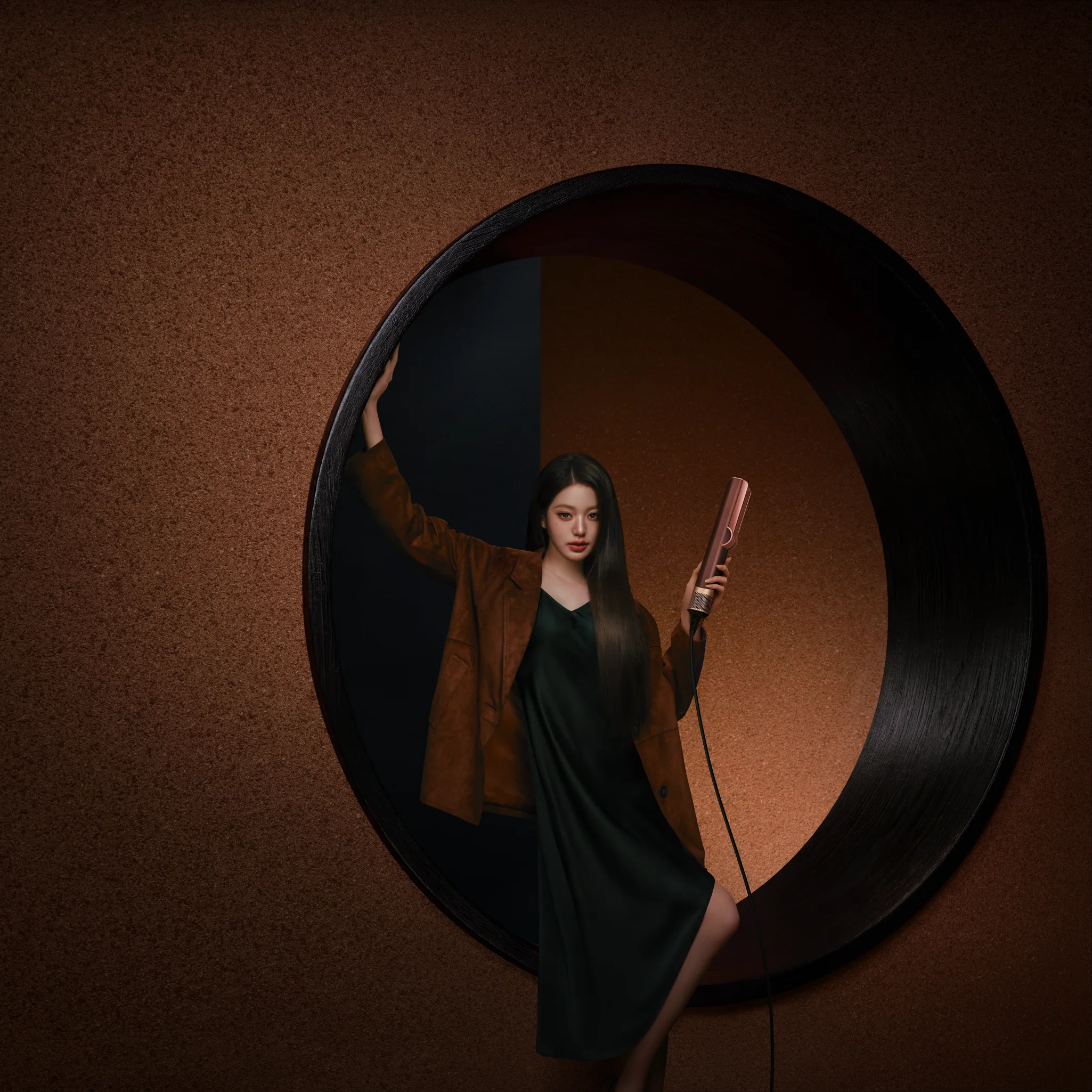 Jang Won Young in a brown jacket and dark green dress holding a Plum and Copper Airstrait inside a round frame
