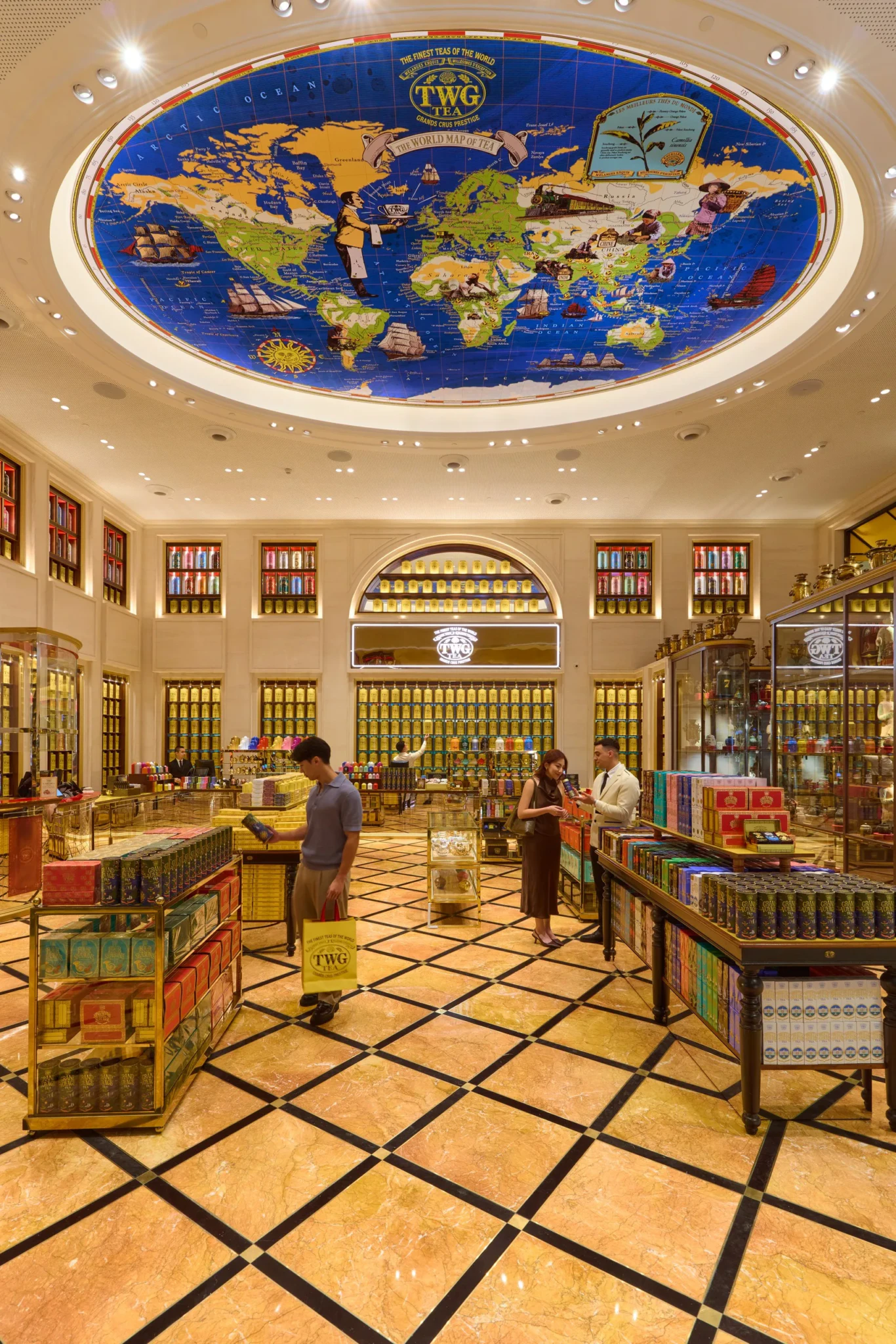 Interior of TWG Tea Gallery with ornate ceiling map, tea displays, and visitors browsing luxury tea products