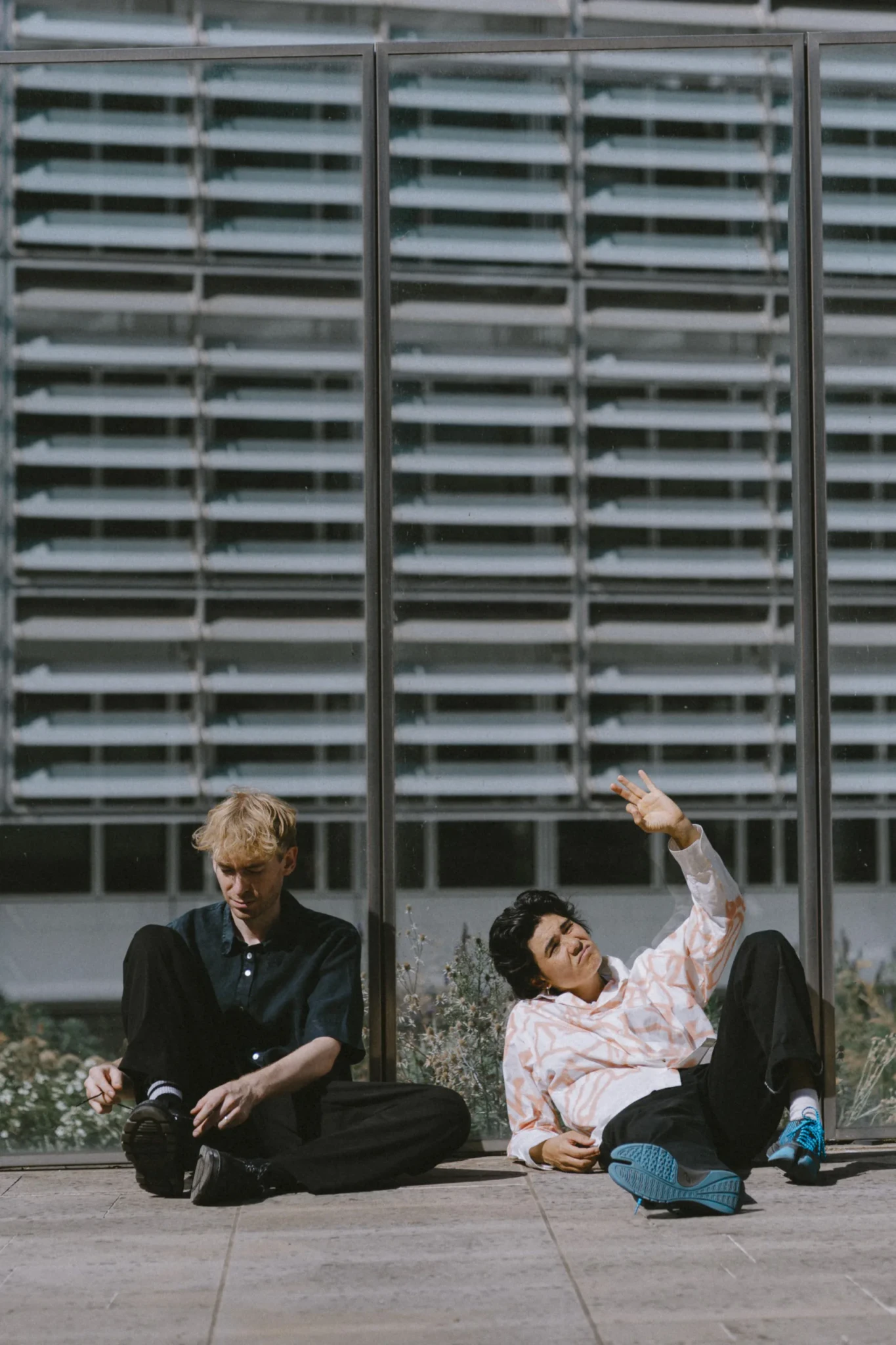Aili & Orson sit on a concrete platform in front of a modernist apartment building