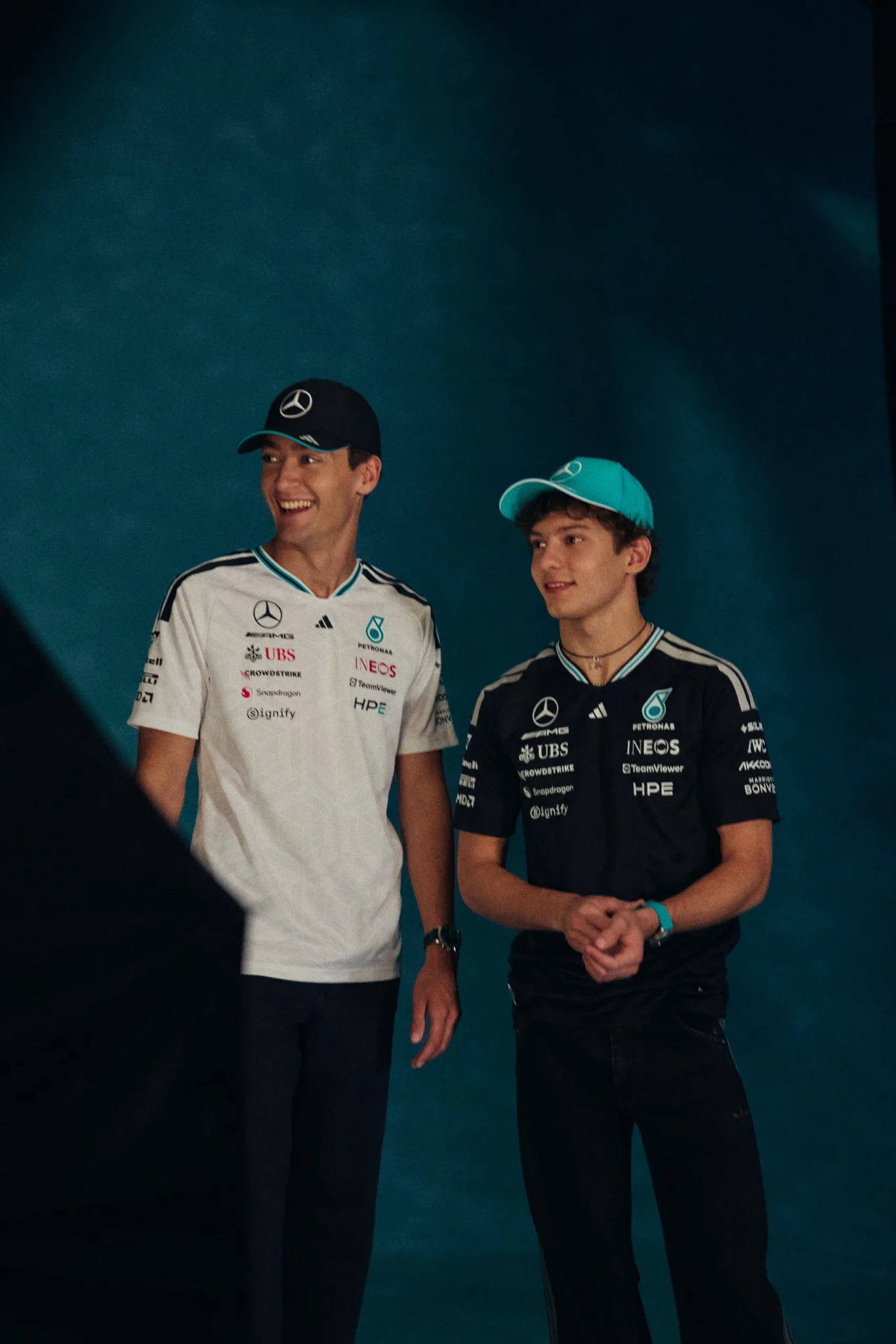 Two F1 drivers in Mercedes team apparel with sponsors visible on their shirts