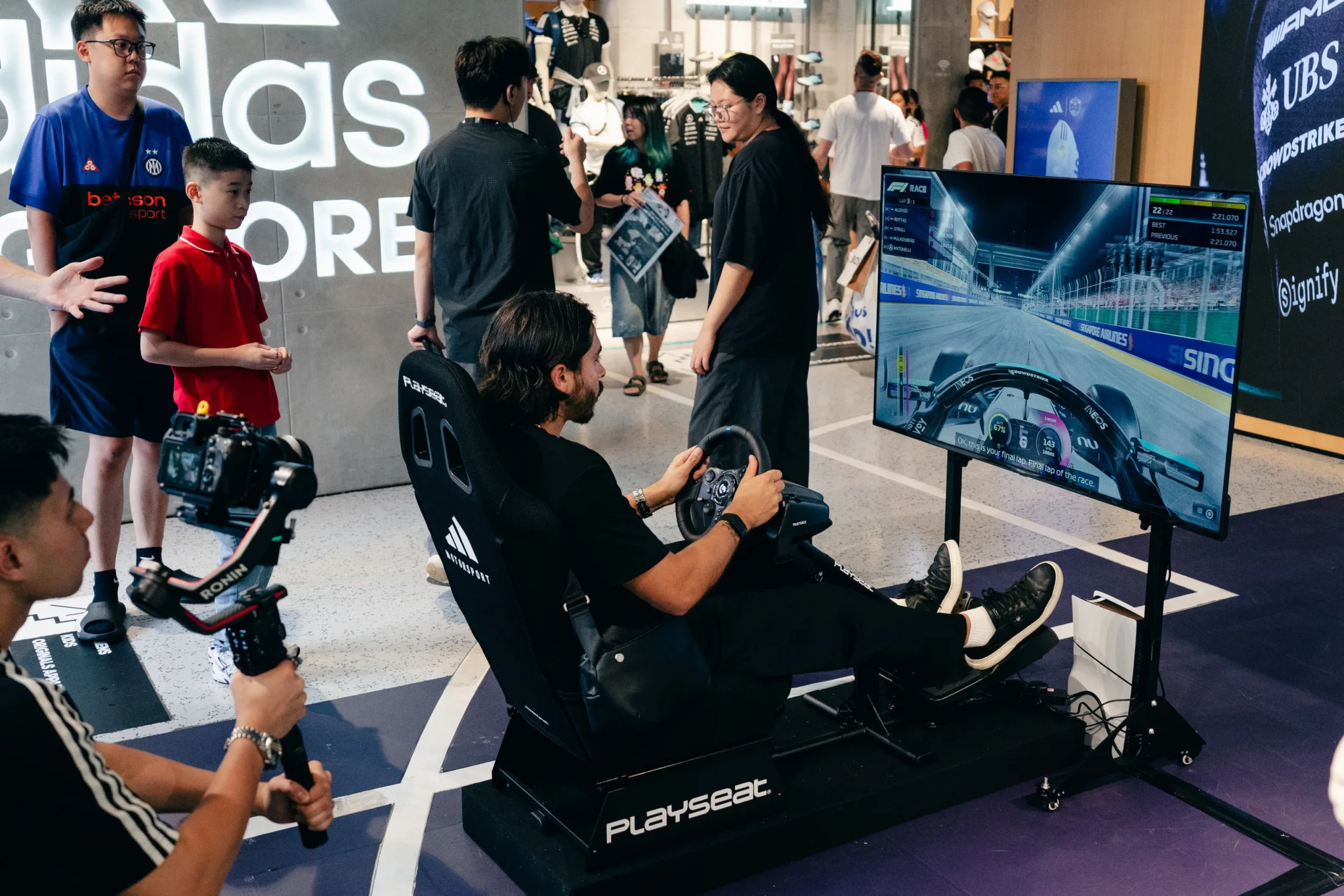 Racing simulator setup at adidas F1 pop-up event with player using steering wheel controller