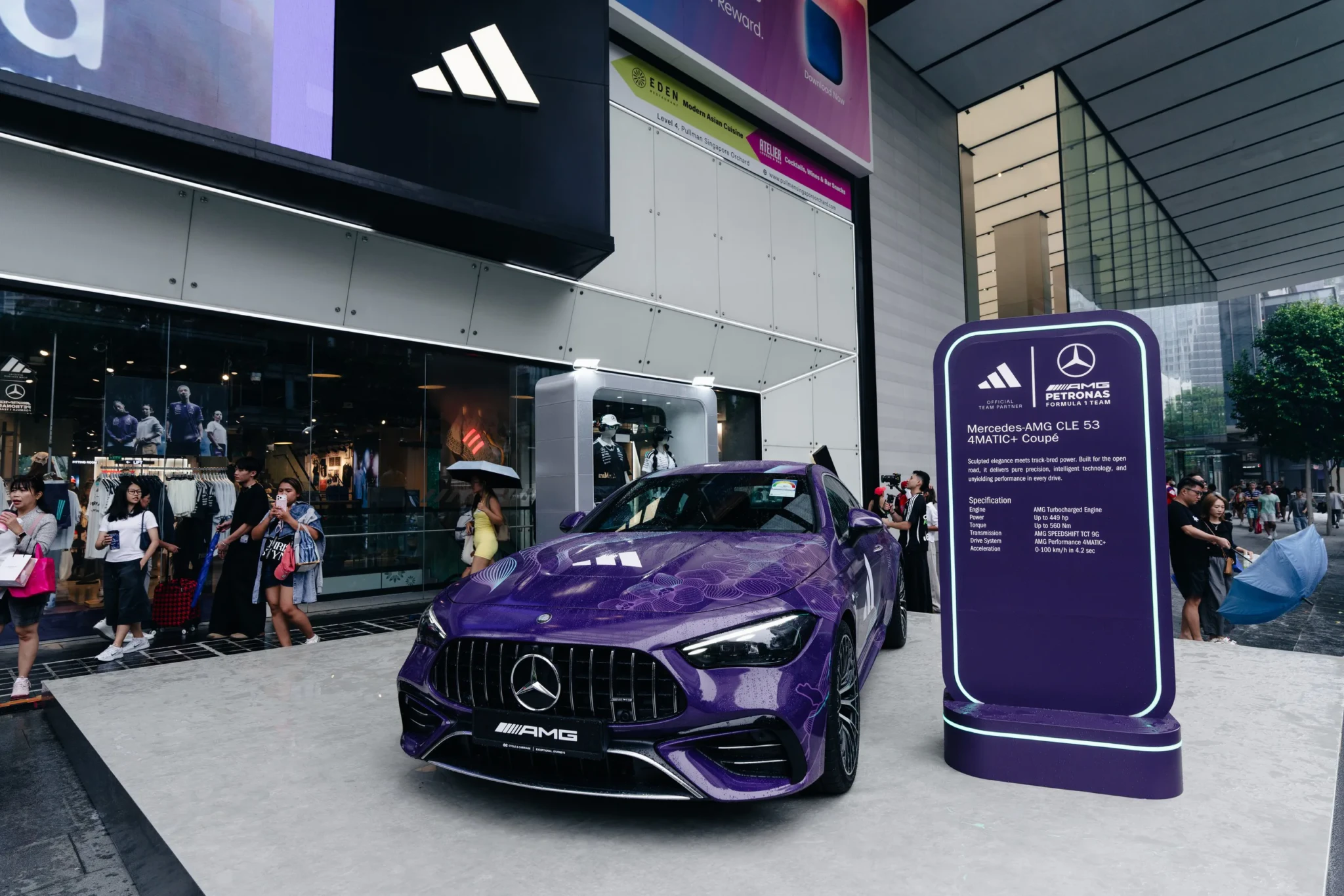 The Mercedes-AMG CLE 53 4MATIC+ Coupé in its purple Vanda Bloom livery outside the adidas store, beside its information placard