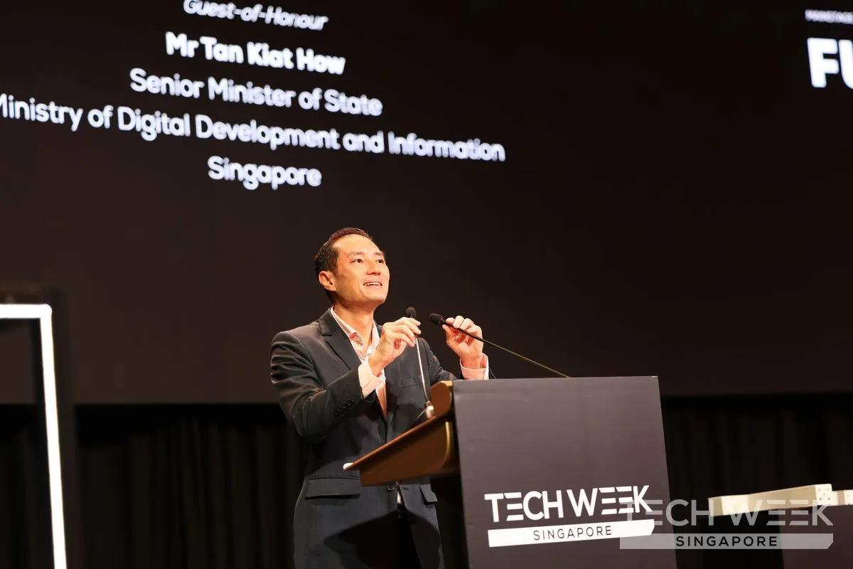 Mr Tan Kiat How speaks at a podium at Tech Week Singapore 2026, his name and title on the screen behind him