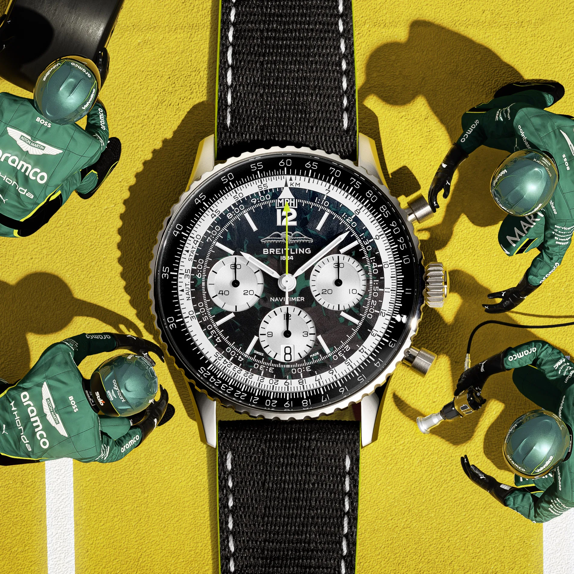 A Breitling Navitimer chronograph with black dial and fabric strap among green Aston Martin Aramco Formula One team merchandise