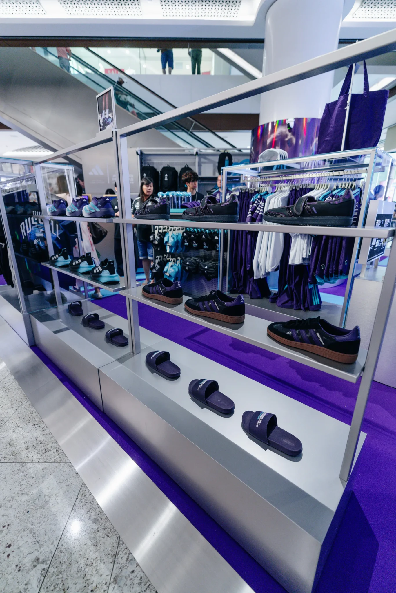 Footwear and apparel arranged on tiered shelving at the adidas x Mercedes-AMG PETRONAS F1 Team pop-up