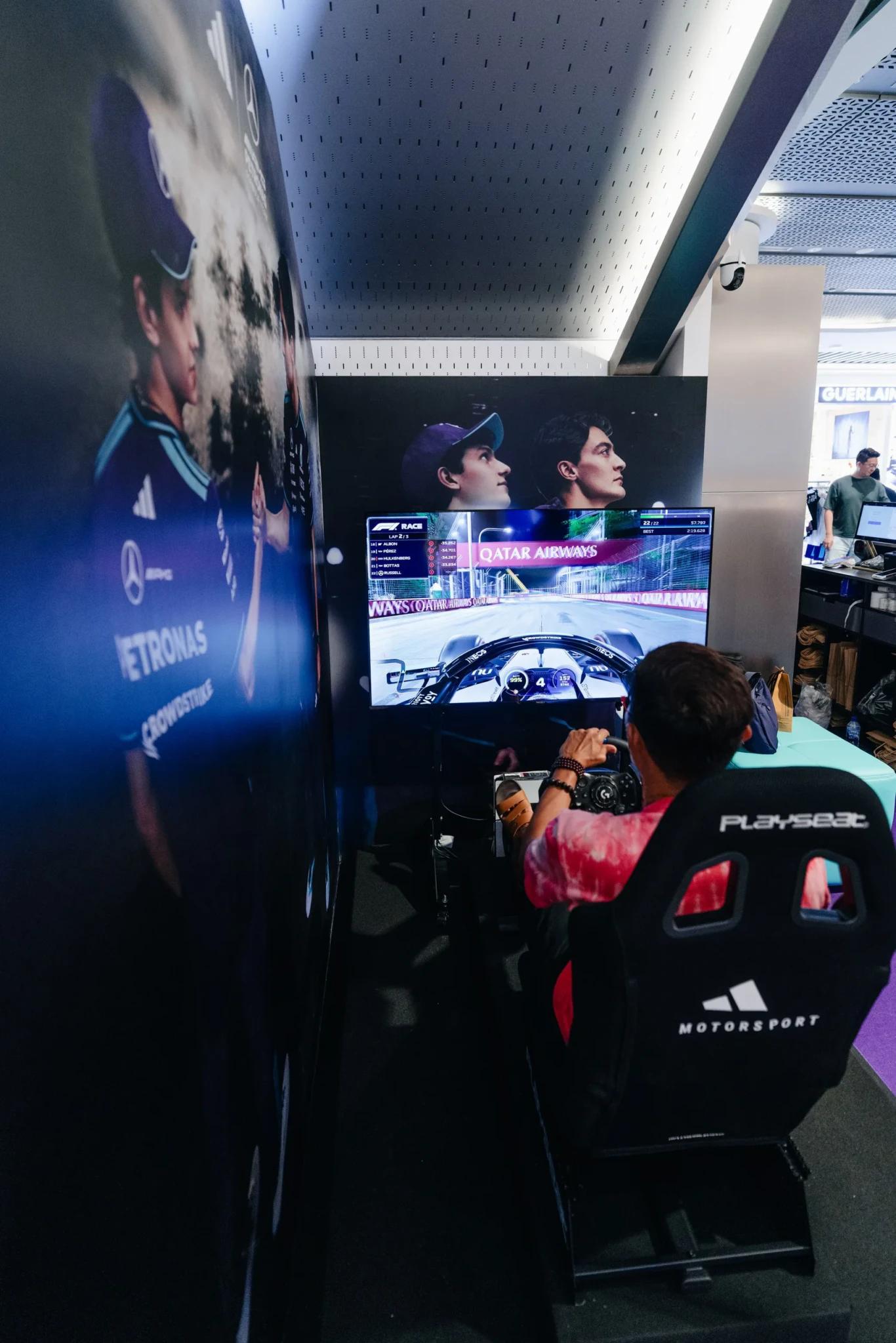 A visitor gripping the steering wheel of a racing simulator at the adidas x Mercedes-AMG PETRONAS F1 Team pop-up