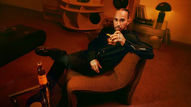 Lewis Hamilton reclining on a curved chair with a glass of Almave