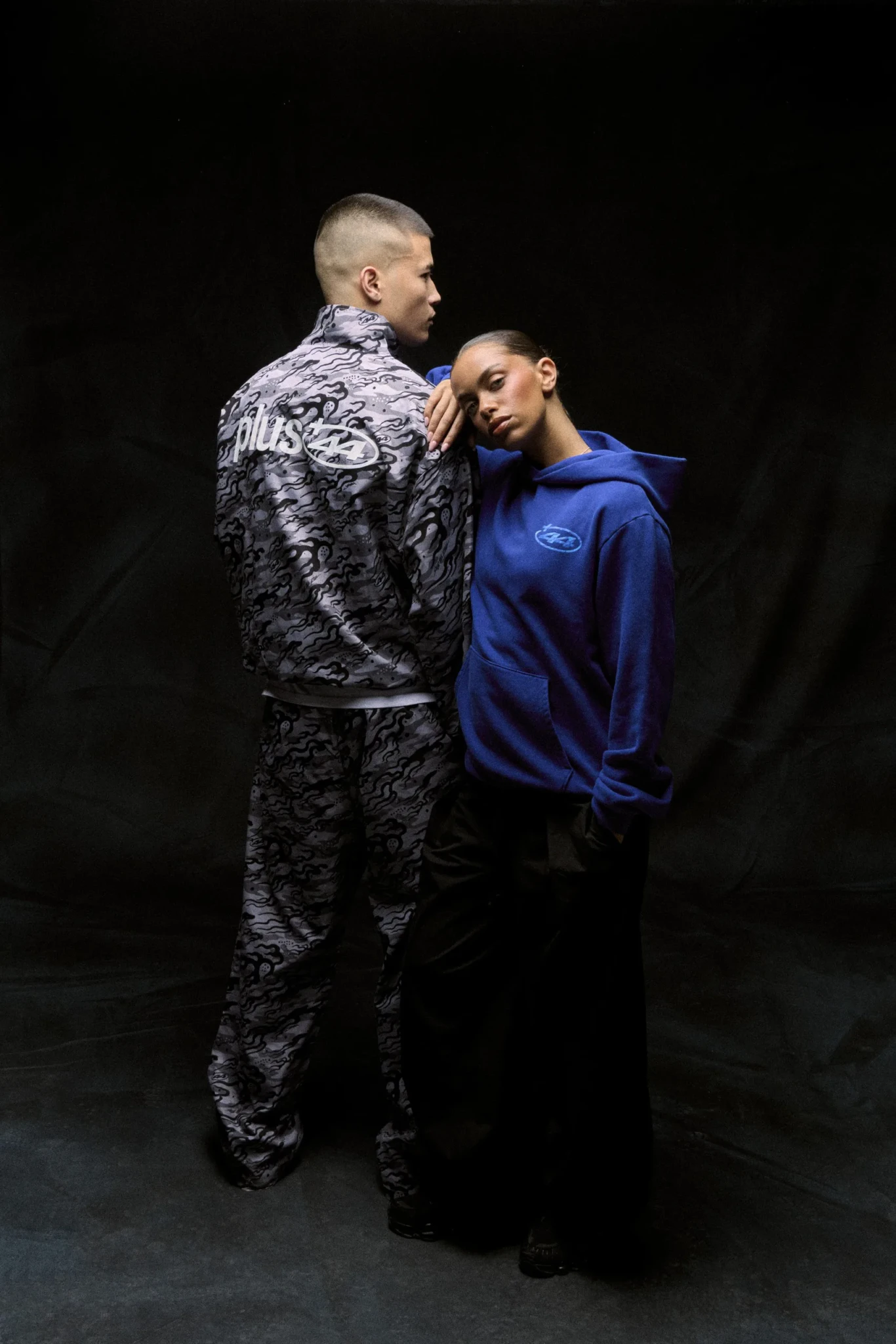Lewis Hamilton in a patterned +44 look beside a model presenting Almave