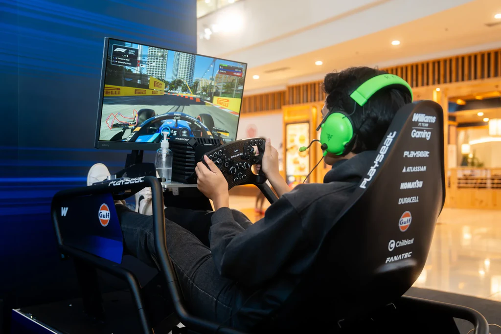 A player in bright green headphones racing at a Williams-branded simulator in the New Era Bugis Junction store