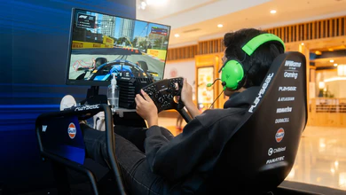 A player in bright green headphones racing at a Williams-branded simulator in the New Era Bugis Junction store