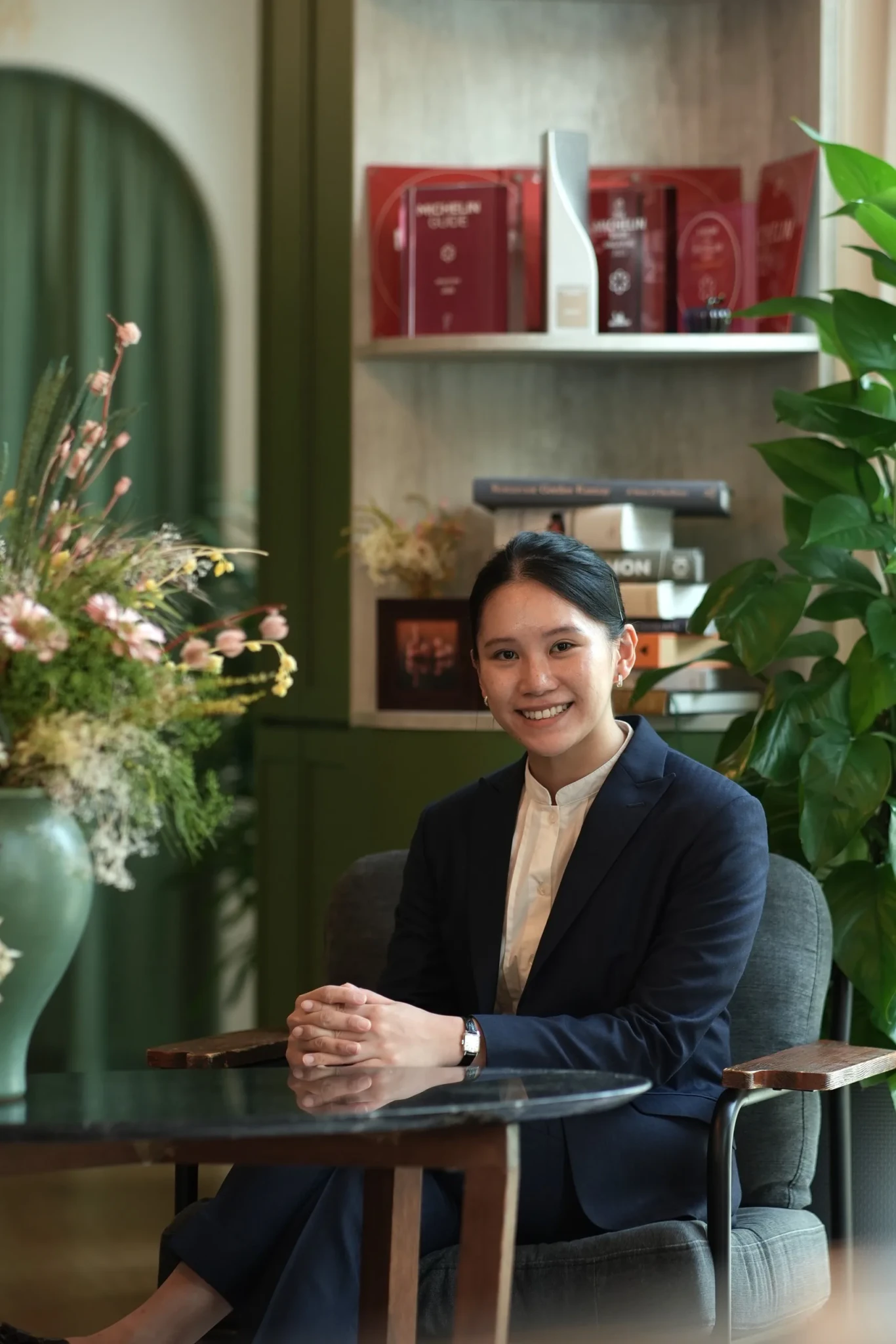 Maryjoy Lim seated at a table in Restaurant JAG's dining room, with plants and shelving behind her