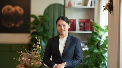 Maryjoy Lim standing in Restaurant JAG's dining room, surrounded by plants and shelving