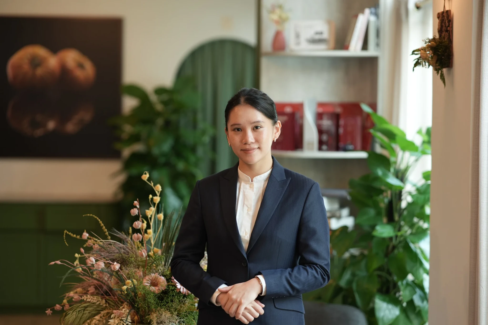 Maryjoy Lim standing in Restaurant JAG's dining room, surrounded by plants and shelving