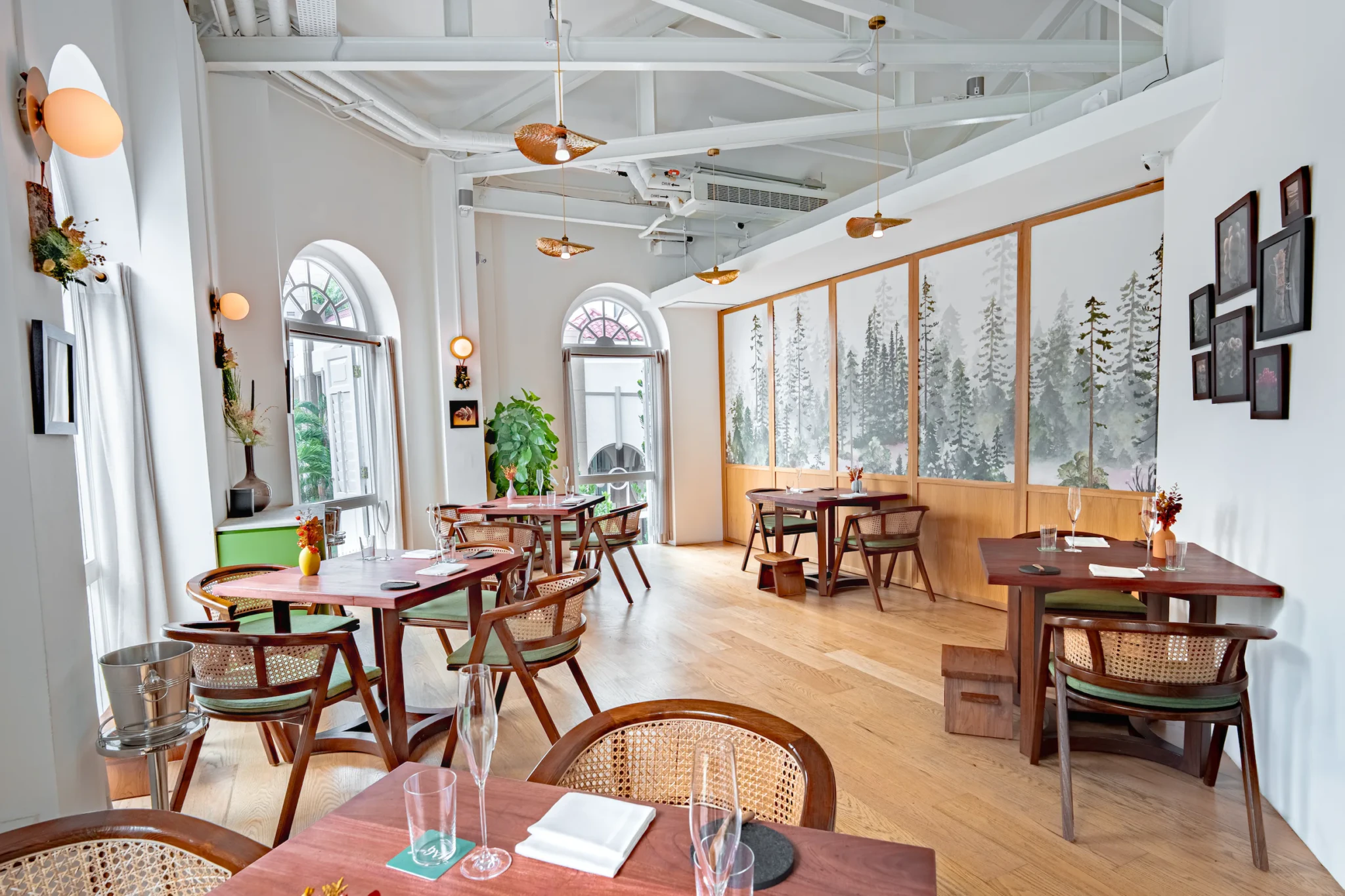 Restaurant JAG's dining room with wooden chairs with woven rattan backs, arched windows, and forest landscape artwork