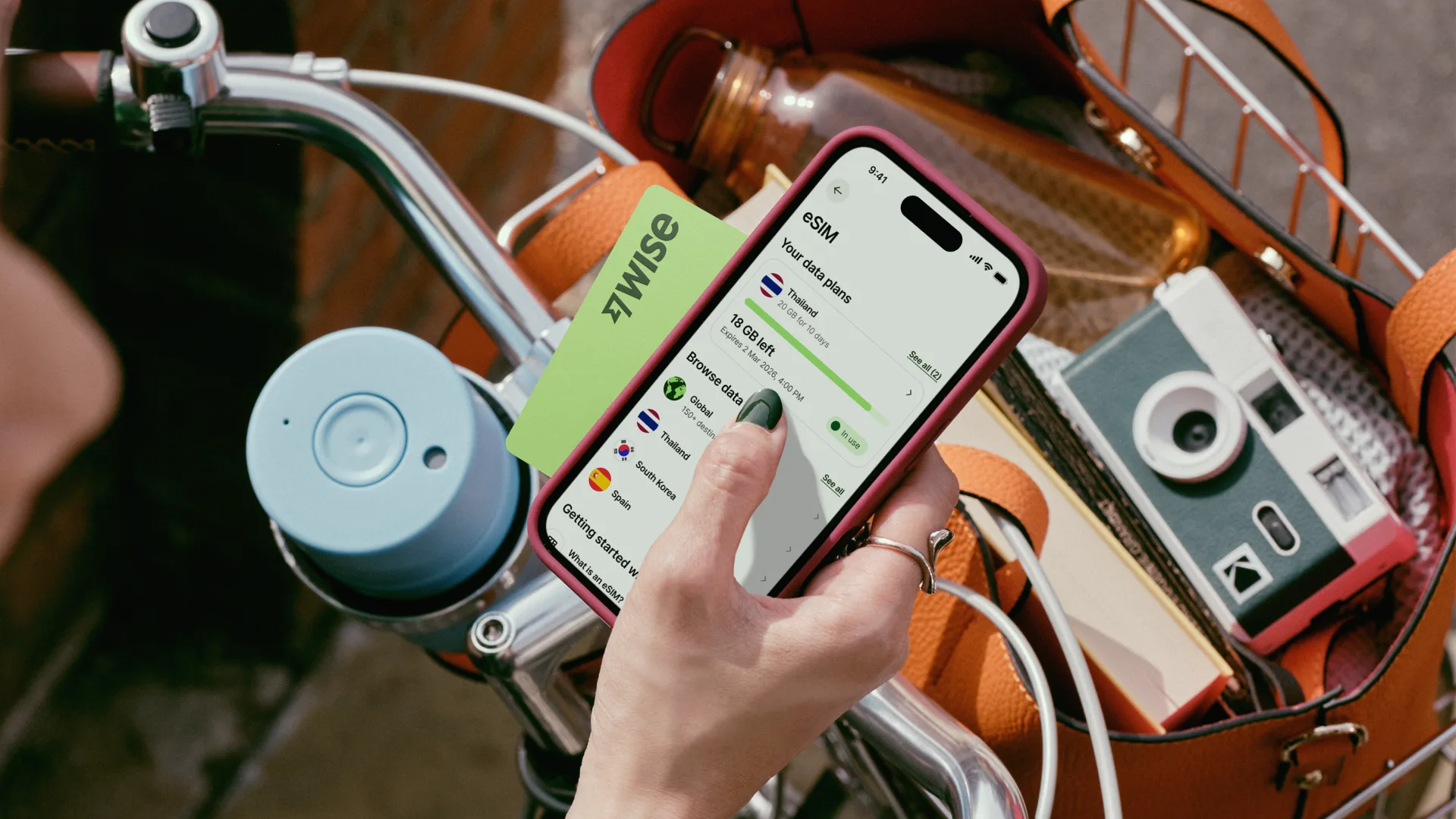 A hand holding a pink-cased smartphone showing the Wise app's eSIM data plans