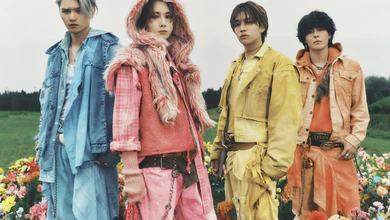 WOLF HOWL HARMONY posing in a flower field in coordinated denim, pink faux fur, yellow, and orange outfits