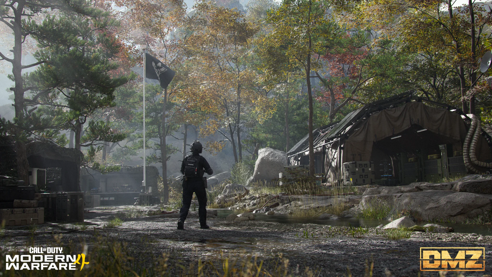 An operator facing a black flag on a pole at the Forward Operating Base, with a military tent and supply crates among autumn trees