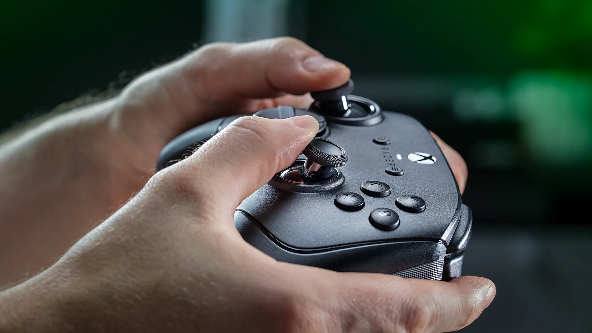 Hands holding the Razer Wolverine V4 controller, showing its thumbsticks and button layout