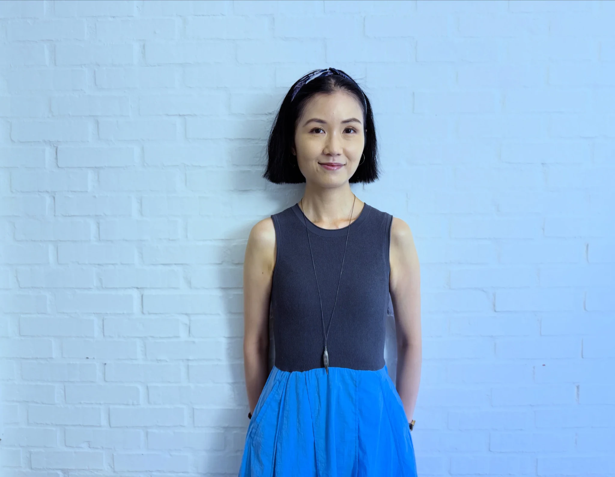 Hon Lai Chu photographed against a light blue brick wall
