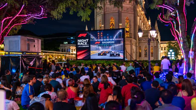 Crowds gathered at CHIJMES for a live screening of the Singapore Grand Prix night race, with neon-lit trees and a large screen showing Formula 1 action