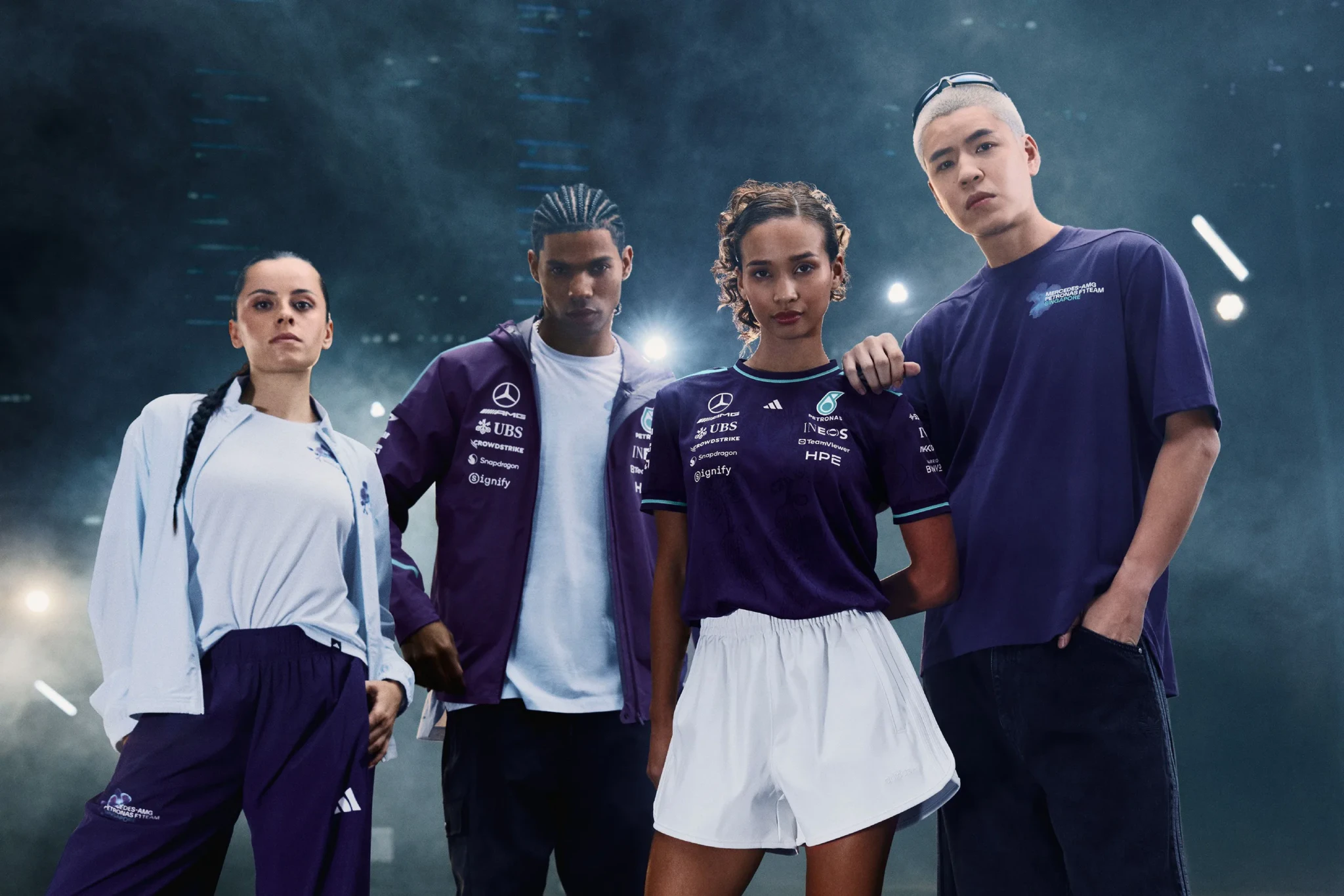 Four models in adidas Mercedes-AMG PETRONAS F1 team wear and merchandise against blue background