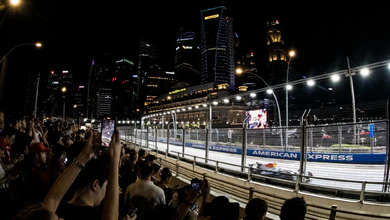 Crowds watch a car pass along the Zone 4 Walkabout trackside, with the Fullerton Hotel behind.