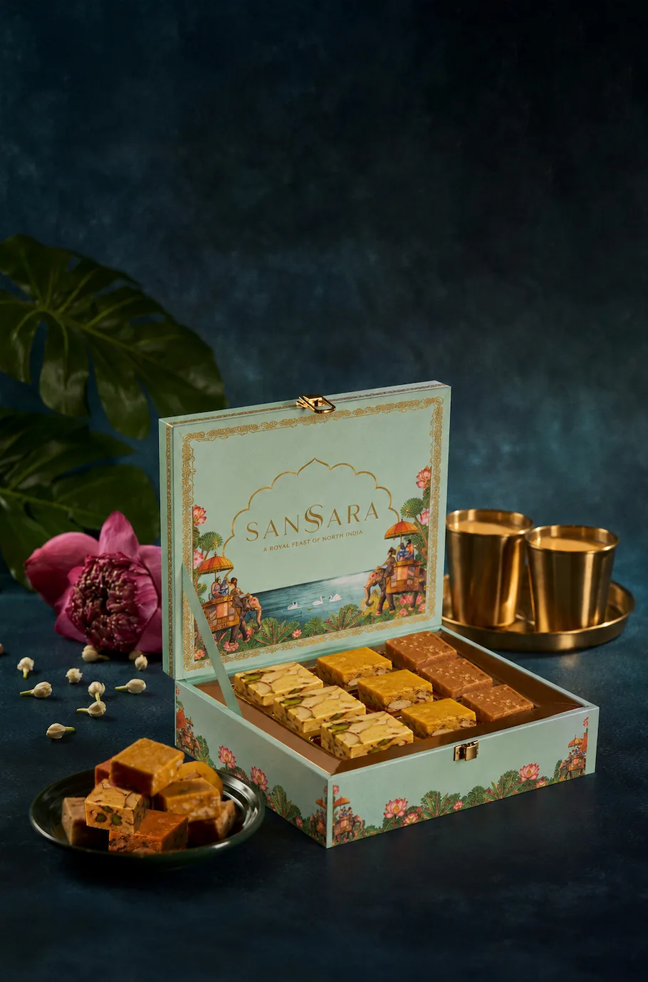 The Diwali Mithai Gift Box from SanSara at Grand Copthorne Waterfront Hotel Singapore, displayed open to reveal assorted Indian sweets, styled with fresh flower