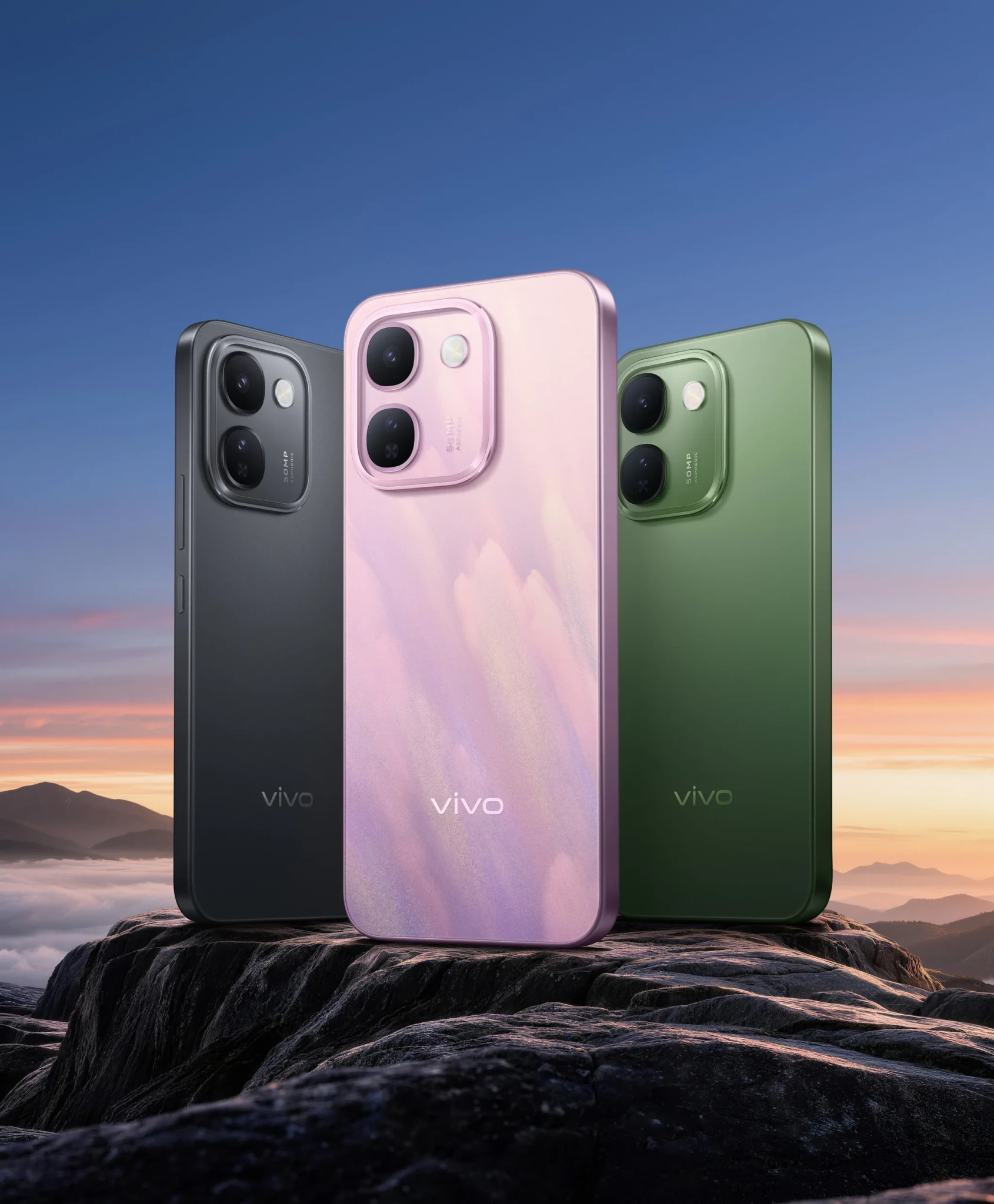 Three vivo V80 Lite 5G phones in black, pink, and green colors on rocks with sunset sky background