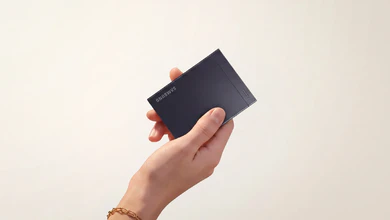 A hand holding the Samsung P9 Portable SSD, a compact black rectangular storage device