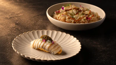 Sliced Abagold abalone with edible flowers and caviar on a shell-shaped ceramic plate, beside a pasta salad, at Capasso