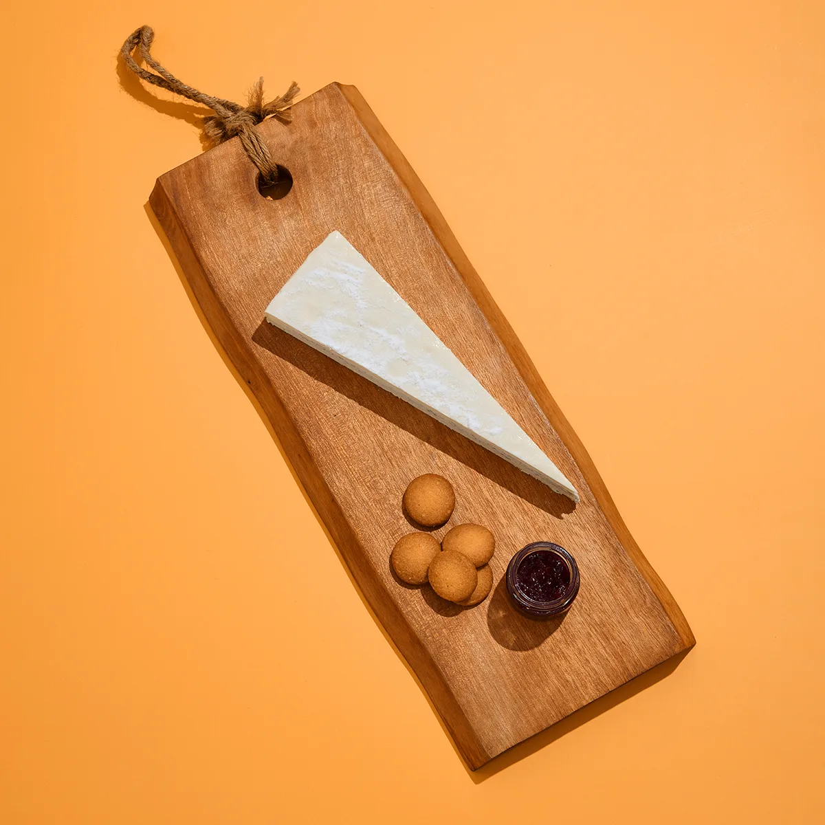 Truffle Brie Cheesecake on a wooden serving board with candied nuts and jam
