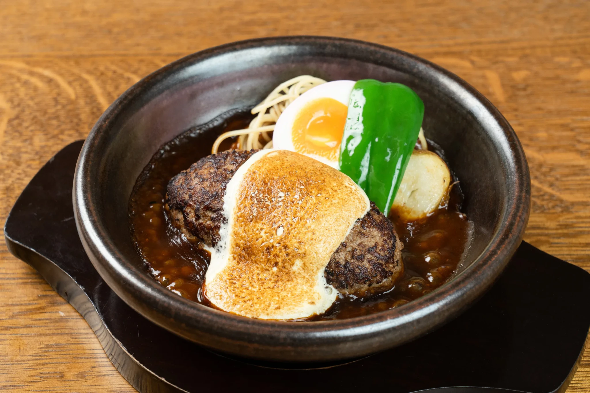 A bowl from Yamamoto's Hamburg topped with a halved soft-boiled egg with a runny yolk, potato, and a green garnish