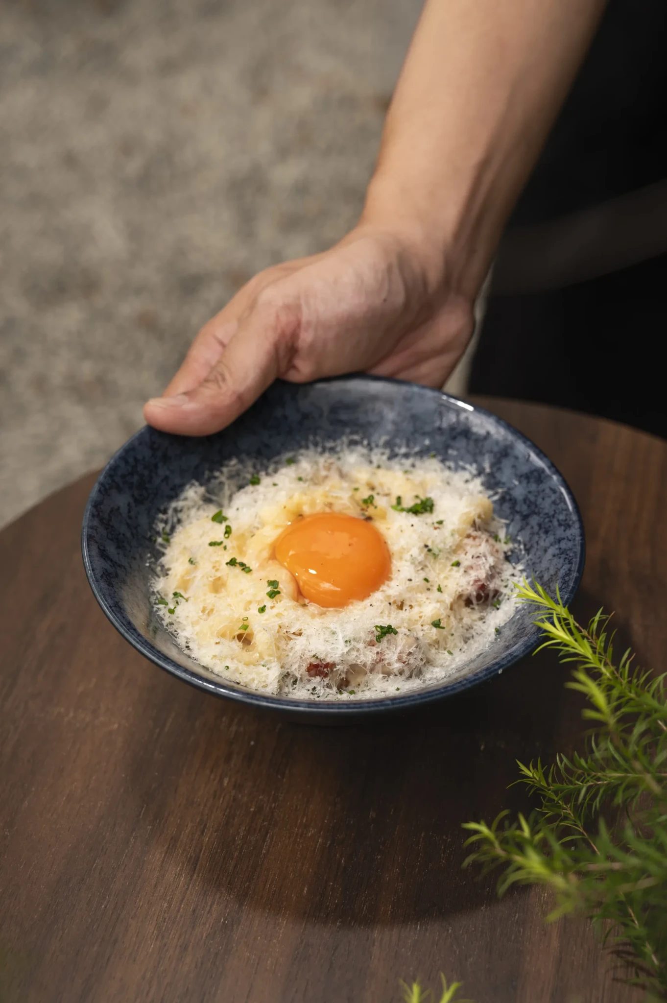 Hokkaido Milk Udon Carbonara in a dark ceramic bowl with a raw egg yolk on top