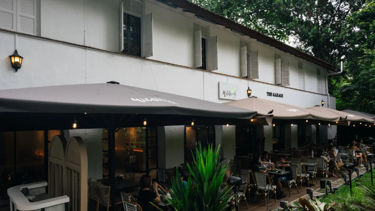 Outdoor seating under umbrellas at Wildseed Café at The Garage, with the café and Garage signs on the white building.