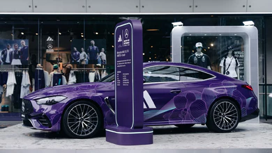 A purple-wrapped Mercedes show car with geometric patterning at a street-level showroom