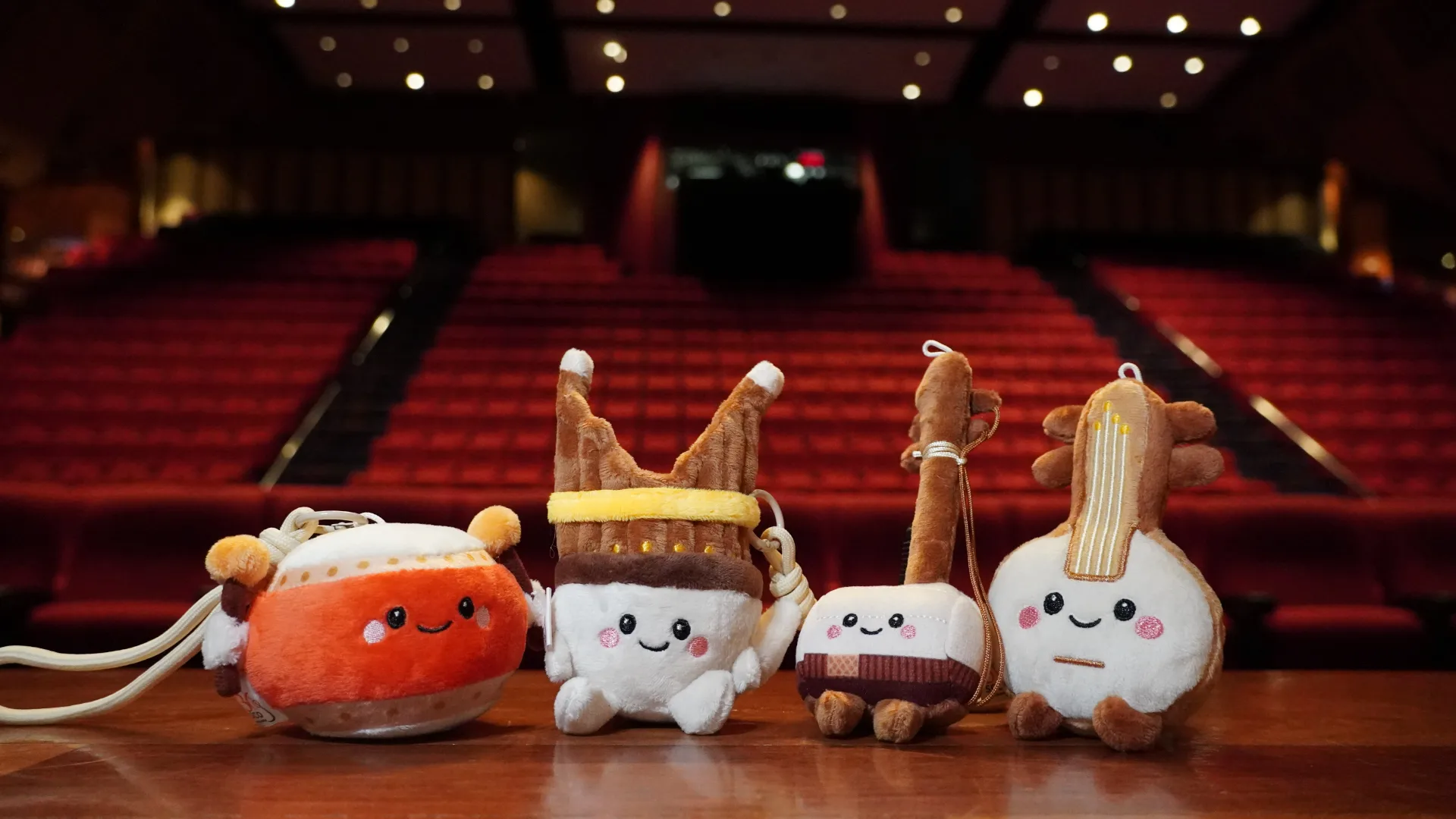 Four plush instrument keychains from SCO's Little Treble Makers set sitting on a concert hall stage