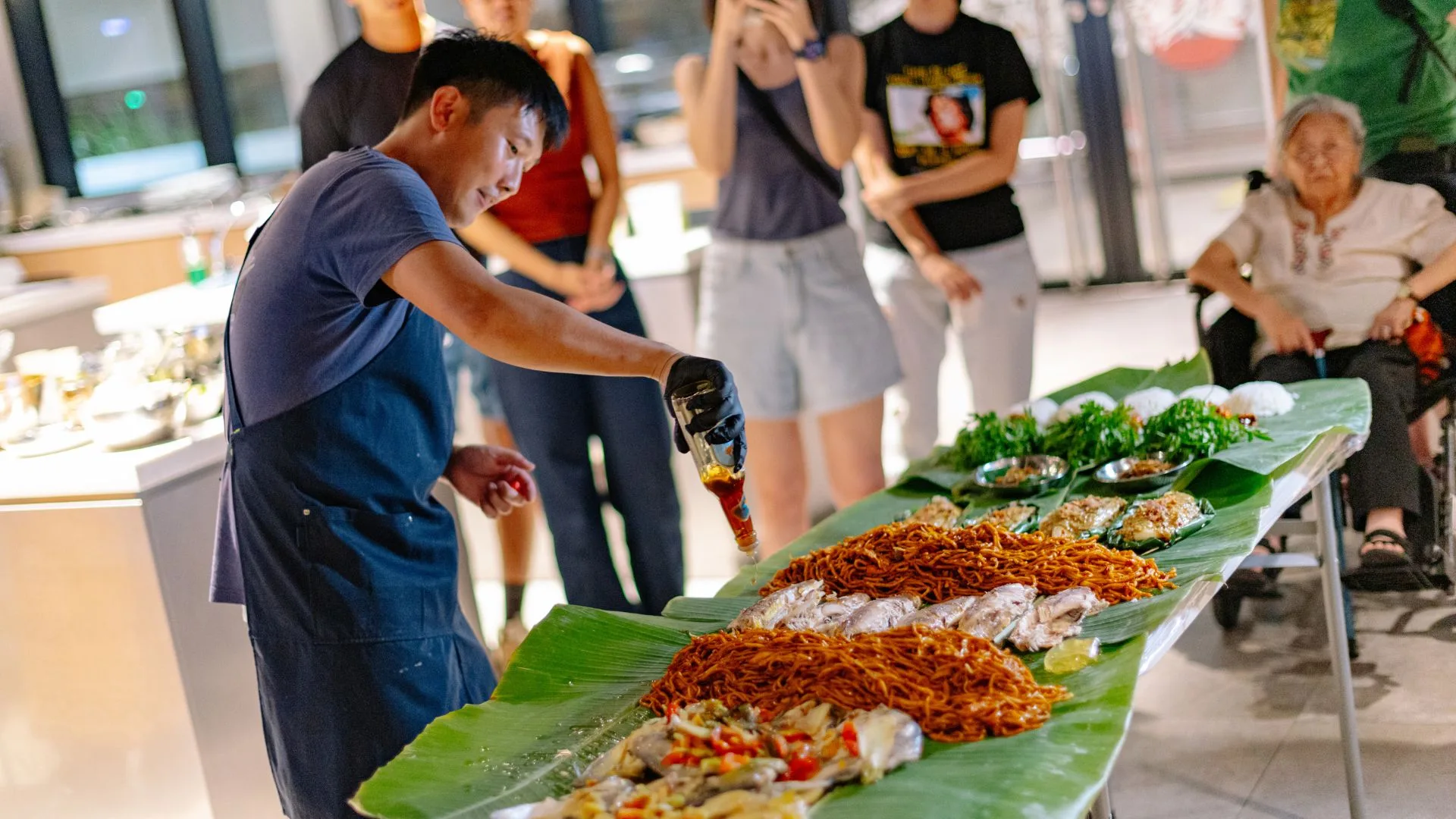 Pasarfish co-founder Kenny Lek pouring sauce over grilled seafood and crispy noodles