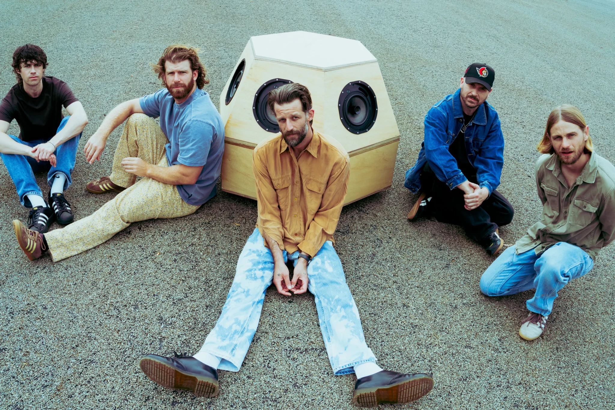 THE RUBENS posing on gravel beside a large wooden speaker cabinet