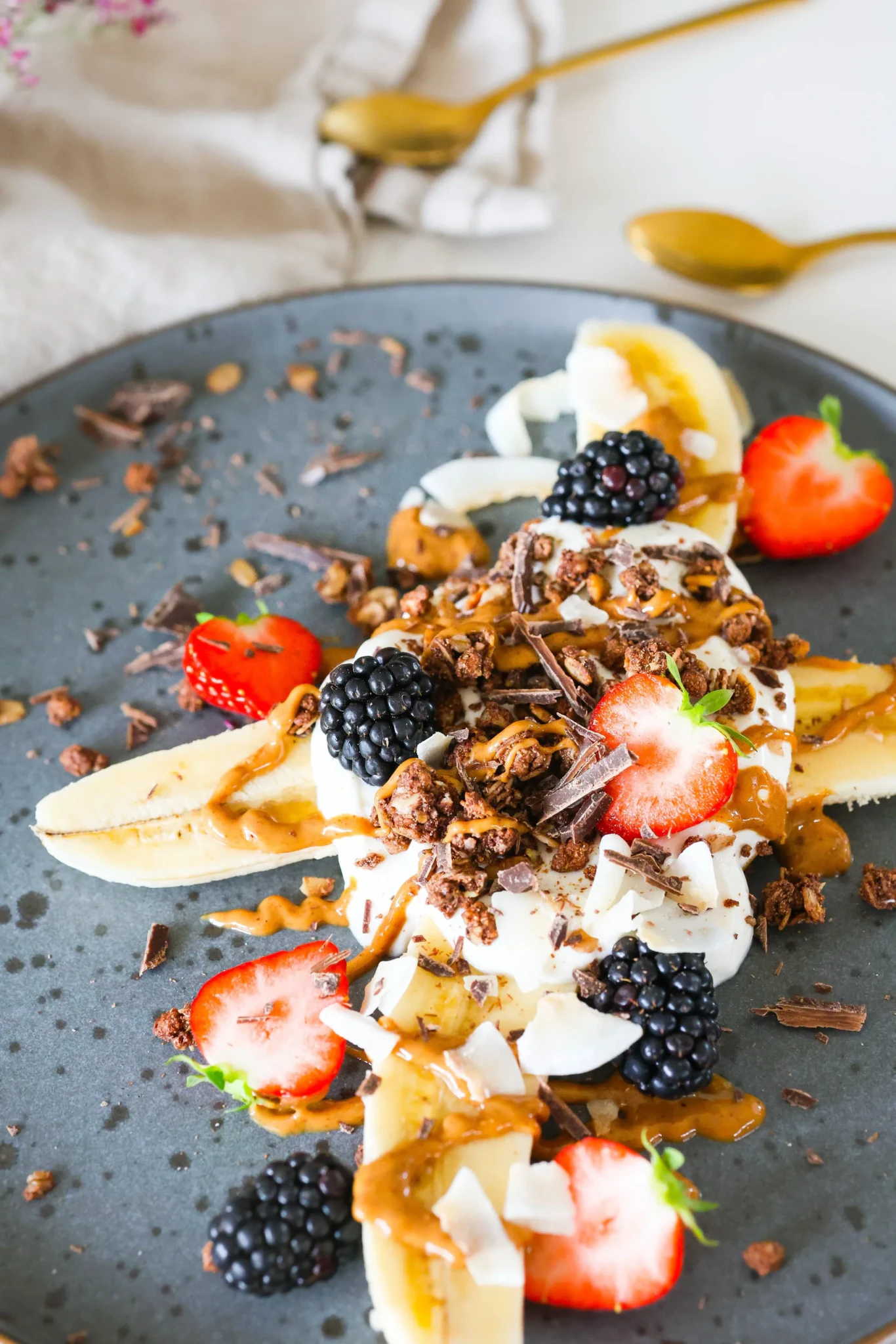 A breakfast banana split topped with skyr, granola, chocolate shavings, strawberries, blackberries and coconut flakes, drizzled with peanut butter