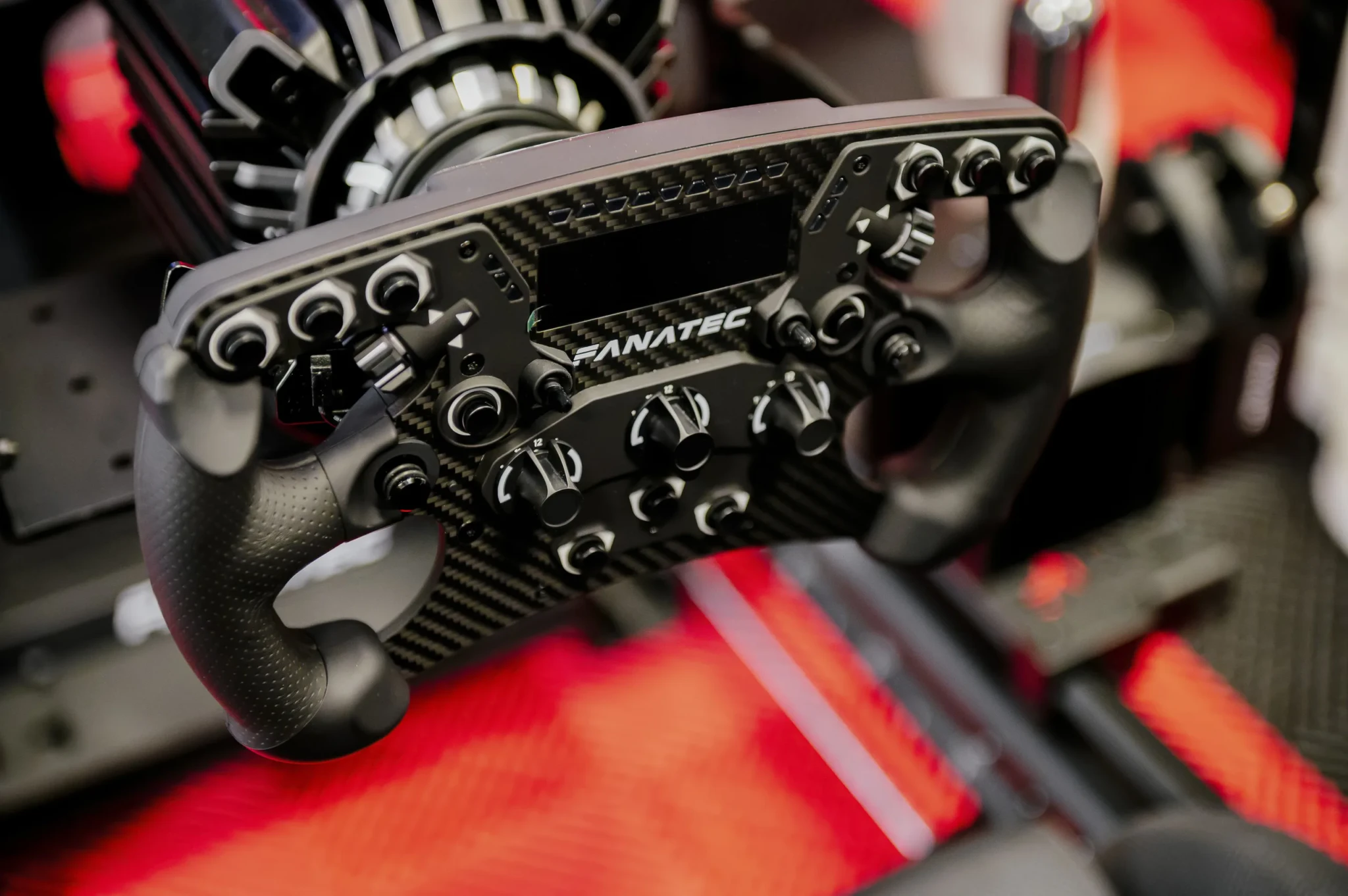 A Fanatec racing wheel with carbon fibre accents held in a pair of hands