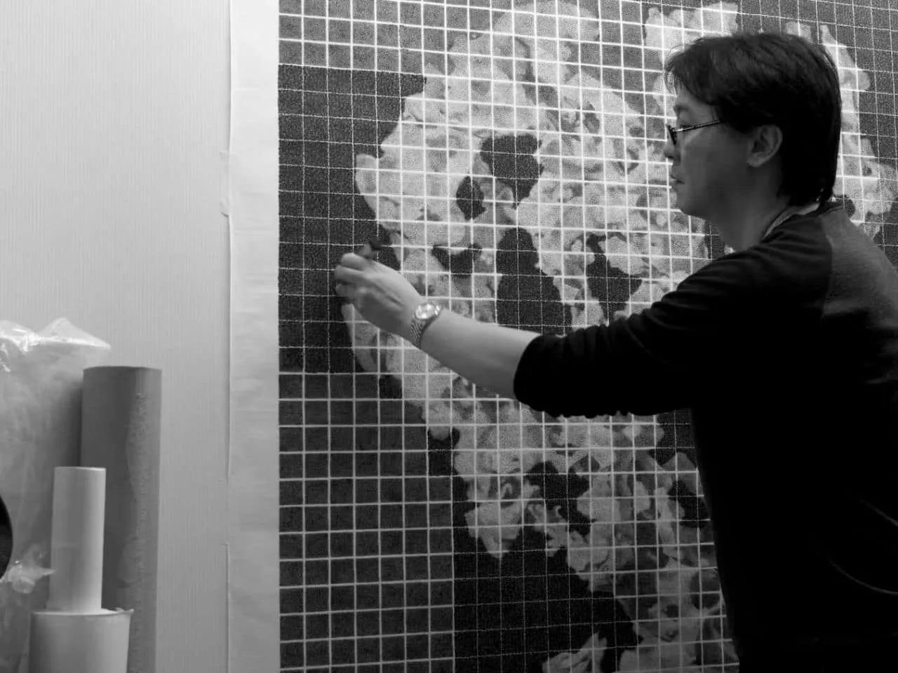 A speaker points to a grid of ink artworks during a presentation on Fan Chang Tien