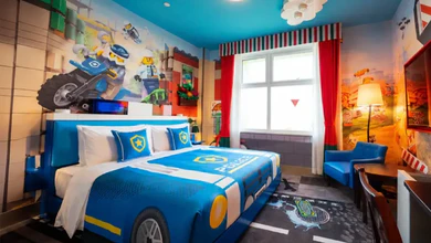 A LEGO CITY-themed hotel room with a blue police-style bed and a motorcycle cop mural