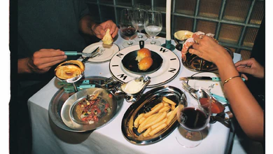 Diners sharing bread rolls, fries, tartare and red wine on a white-clothed table at Win Win in Etta The Place, Berawa