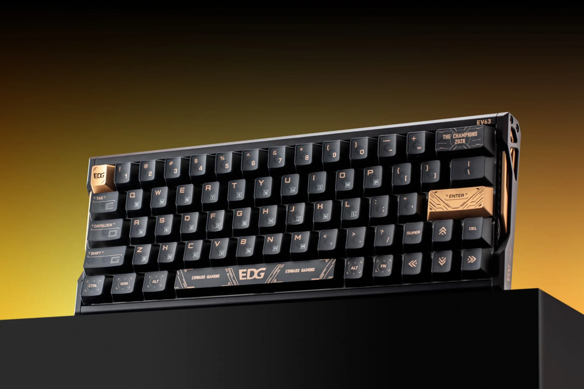 The IQUNIX EV63 EDG Edition on a black stand against a gold gradient, with a THE CHAMPIONS 2026 keycap