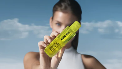 Biotherm Aquasource+ Electrolyte Dewy Gel bottle held up against a blue sky with clouds