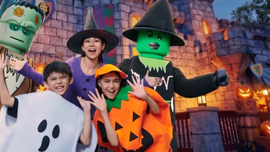 A family in Halloween costumes with the LEGO Frankenstein and Witch in front of the castle at LEGOLAND Malaysia Resort during Brick-or-Treat.